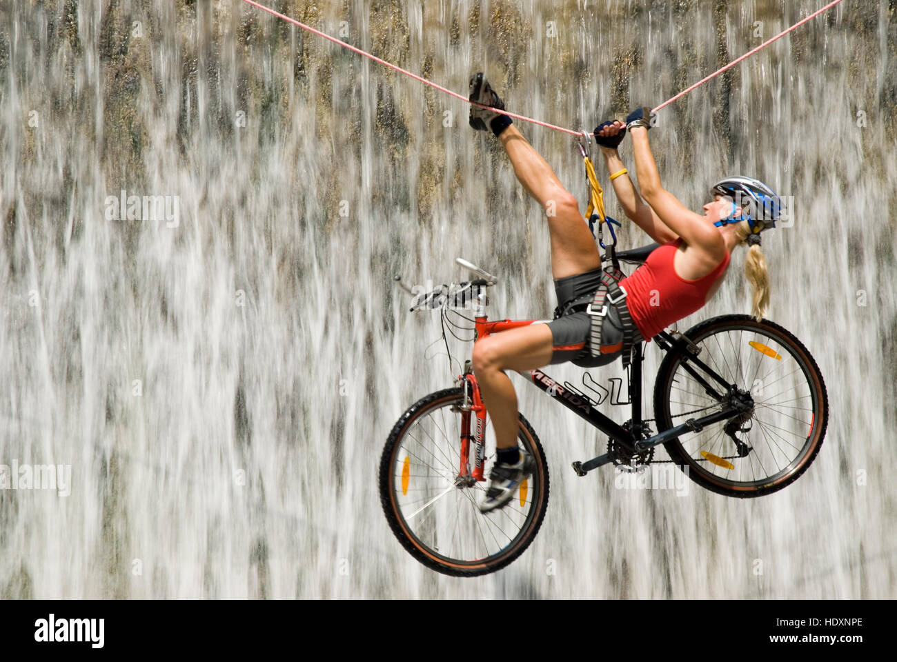 Woman crossing a waterfall on a rope with a bike, Kalkalpen National Park, Upper Austria, Austria, Europe Stock Photo