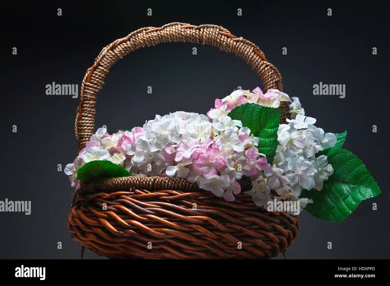 Basket of artificial flowers against black background Stock Photo