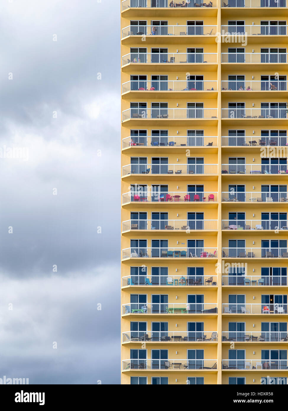 A pattern of bright, yellow condominium balconies against a gray cloudy sky. Stock Photo