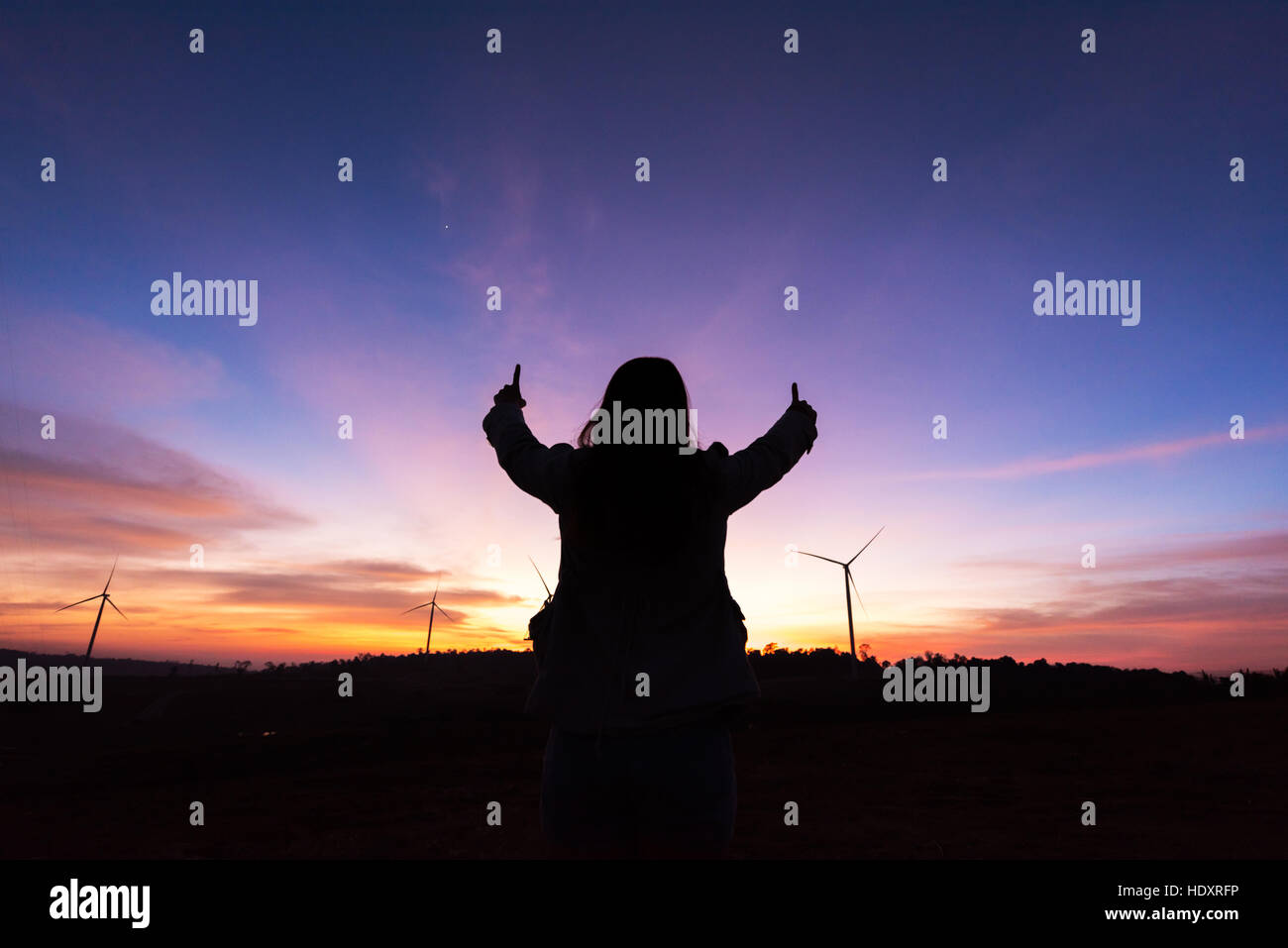 Silhouette tourist woman raised hand to sunset on the turbine at reservoir in low light Stock Photo