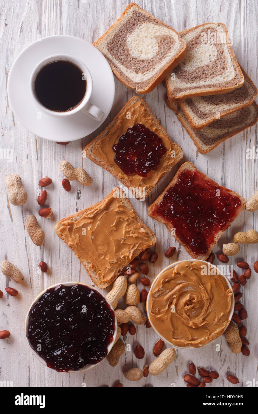 Sweet sandwiches with jelly, peanut butter and coffee close-up on the table. vertical top view Stock Photo