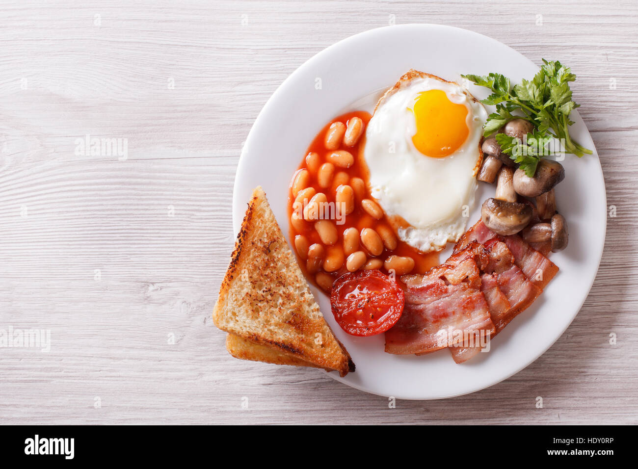 Fried egg with bacon, beans and toast on a plate. horizontal view from above Stock Photo