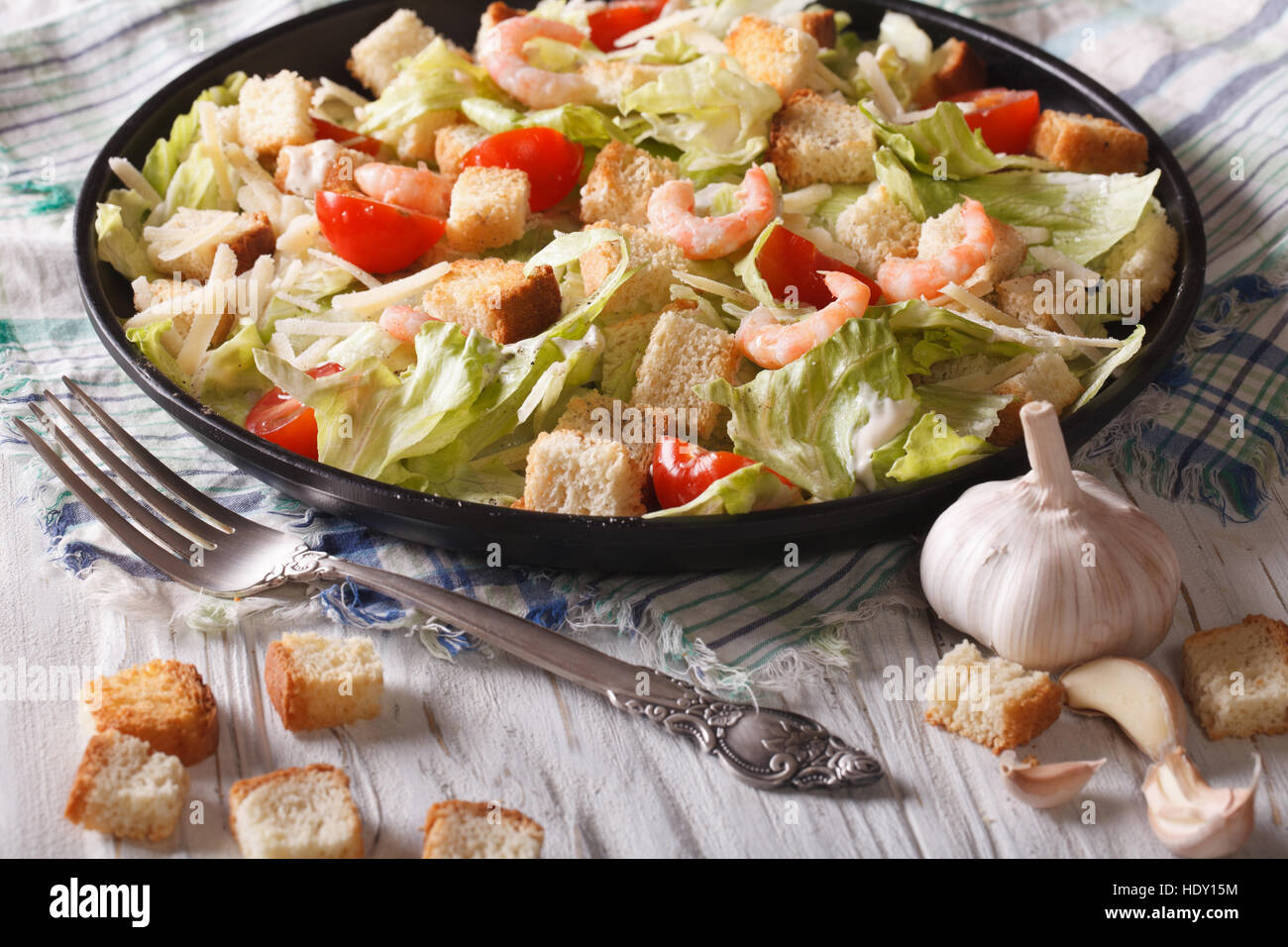 Fresh Caesar salad with shrimp and tomatoes close up on black plate. horizontal Stock Photo