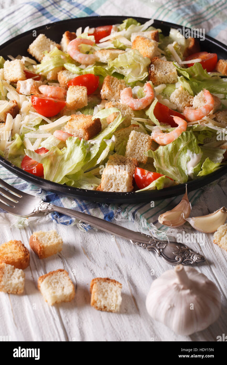 Delicious Caesar salad with shrimp and tomatoes close-up on a plate. vertical Stock Photo