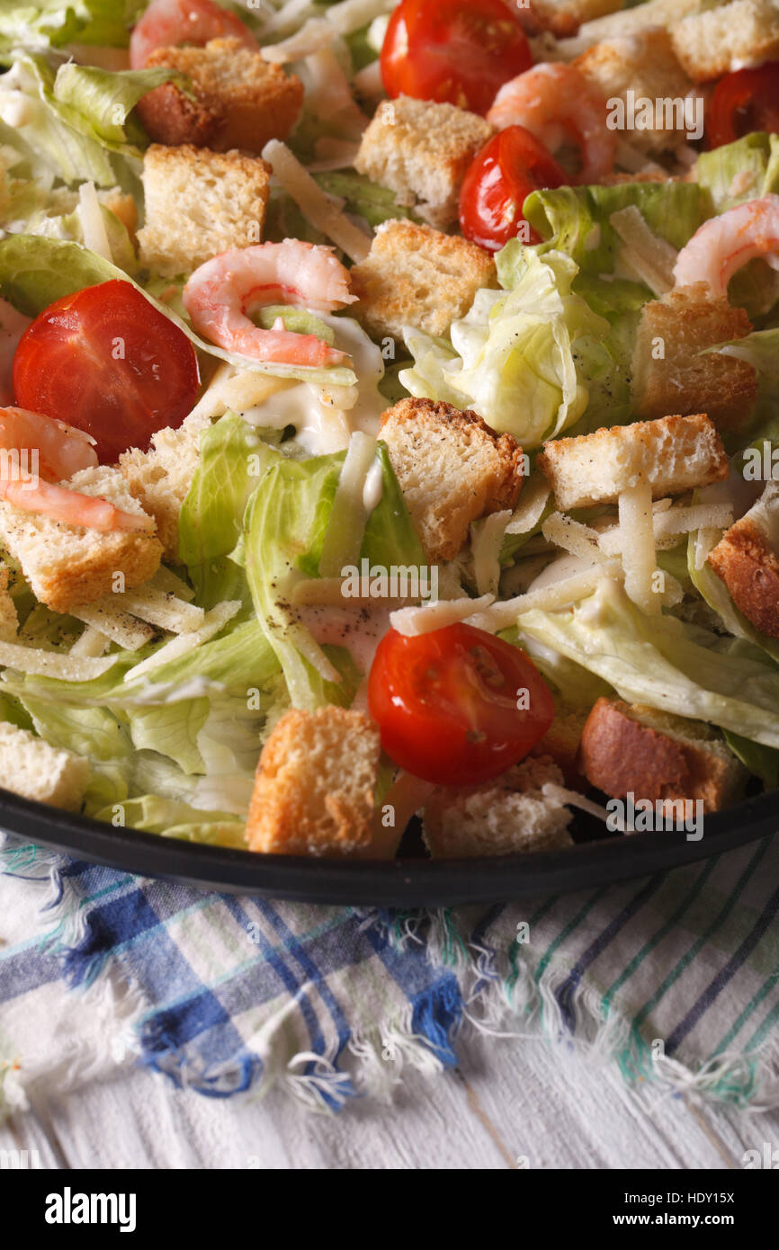 Caesar salad with shrimp and tomatoes close-up on a plate. Vertical Stock Photo