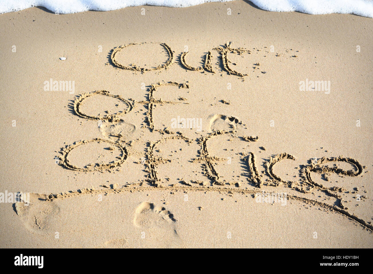 Out of office text written in sand on a beach suggesting work life balance Stock Photo