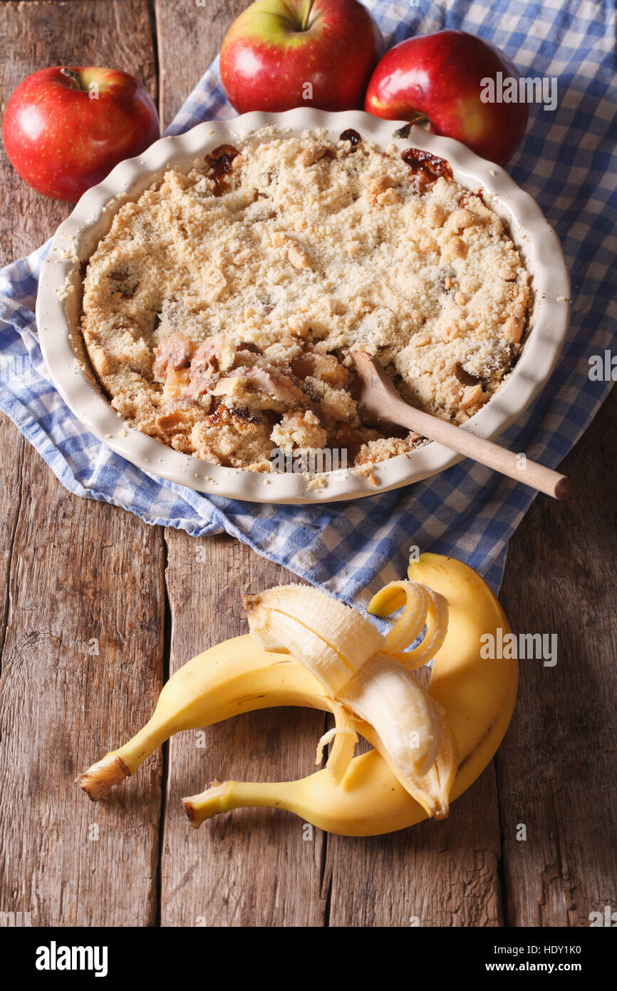 Crumble with apple and banana close up in baking dish. Vertical, rustic style Stock Photo