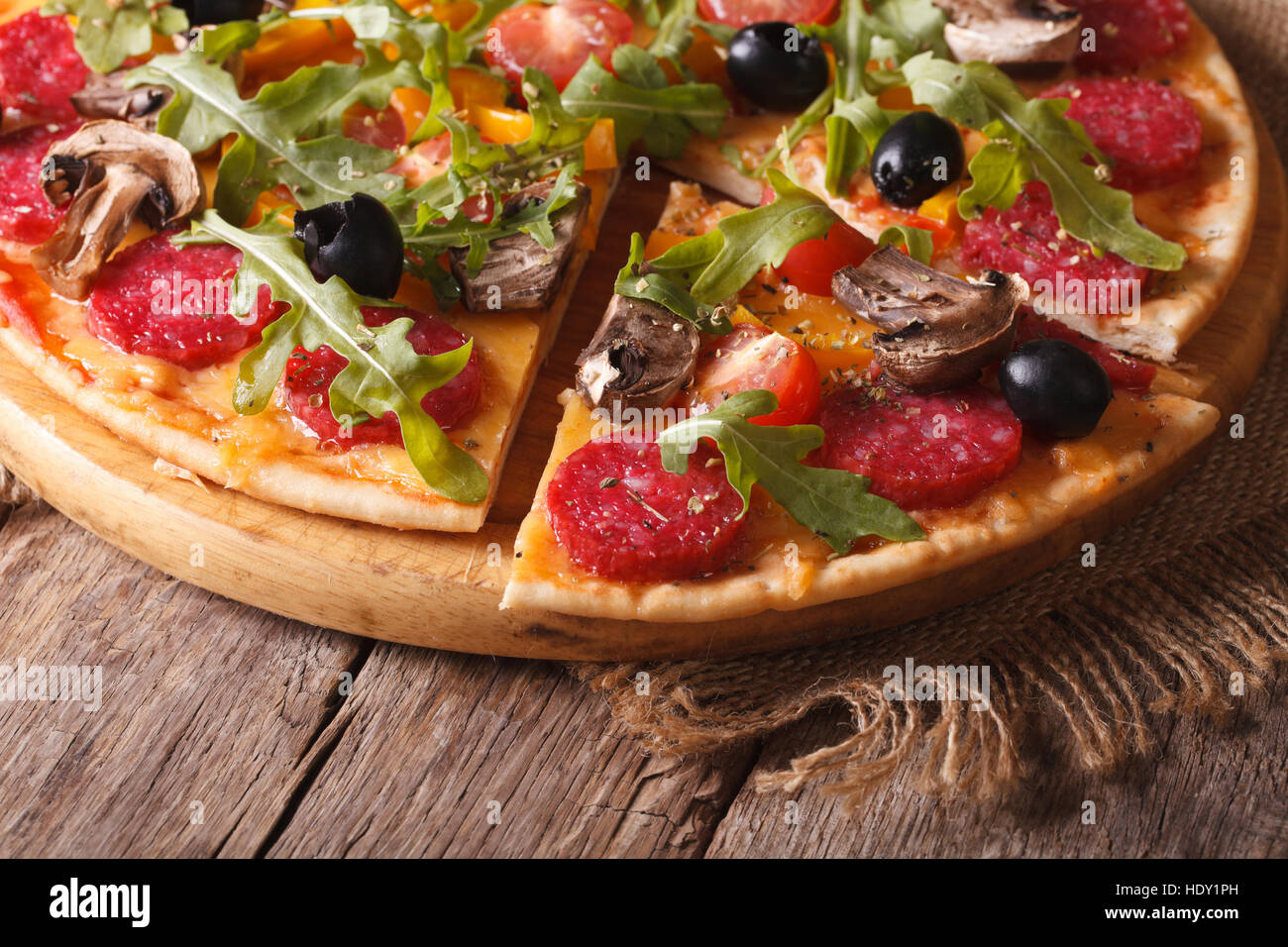 Pizza with rucola, salami and olives close-up on the table. horizontal, rustic style Stock Photo