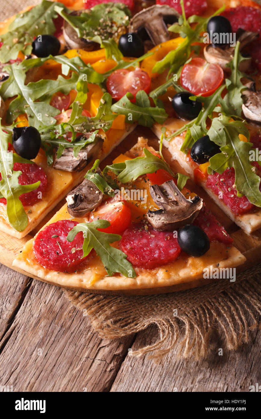 Pizza with rucola, salami and olives close-up on the table. vertical top view Stock Photo
