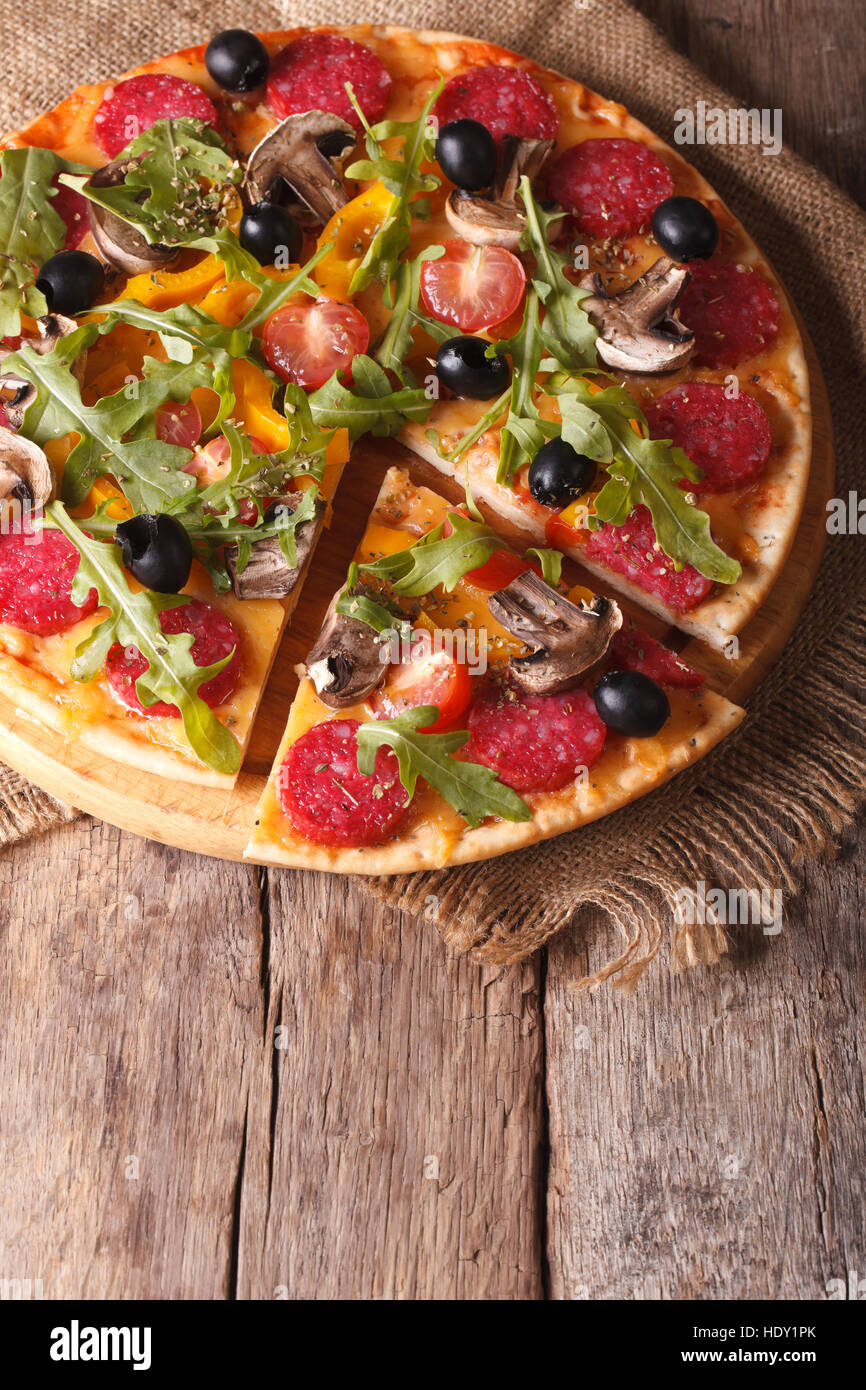 Pizza with rucola and salami close-up on the table. vertical top view Stock Photo