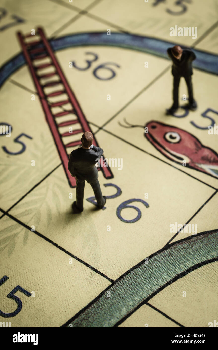 Business men pondering success and failure on a snakes and ladders board a problem solving concept Stock Photo