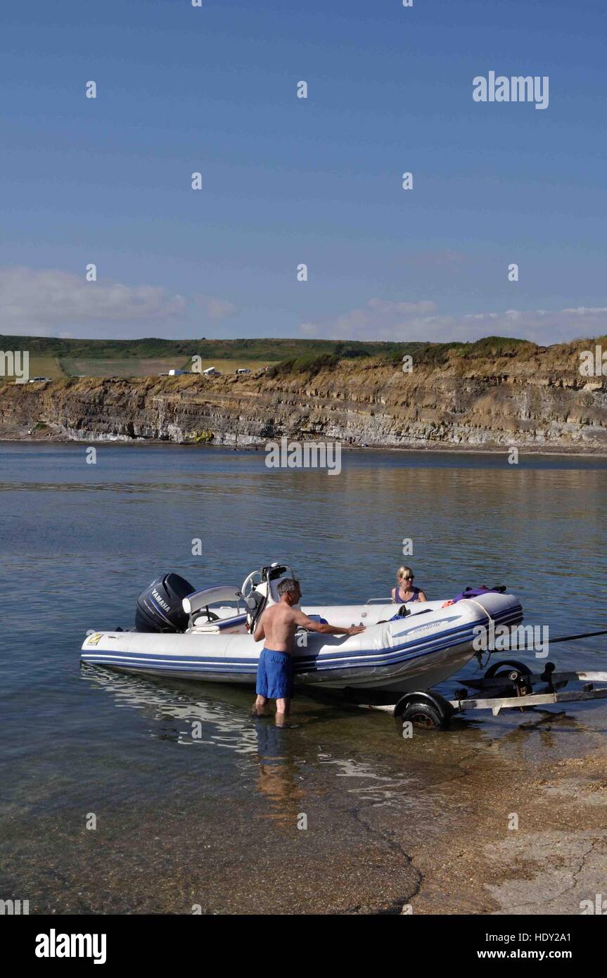 A man and woman guide a rigid inflatable boat back onto its trailer at Kimmeridge, Dorset. Stock Photo