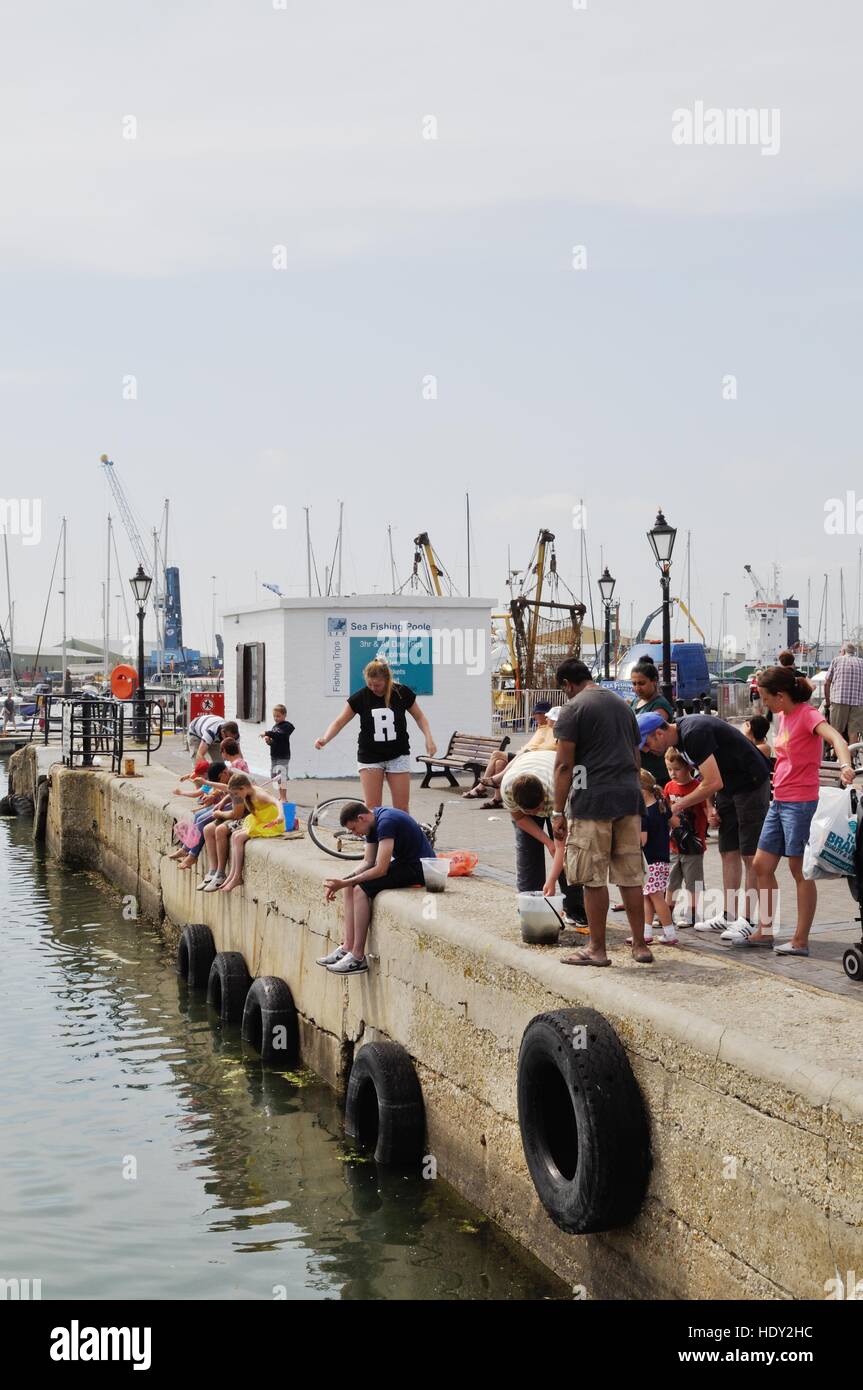 Crab fishing is a popular summer pastime on Poole Quay, Dorset Stock
