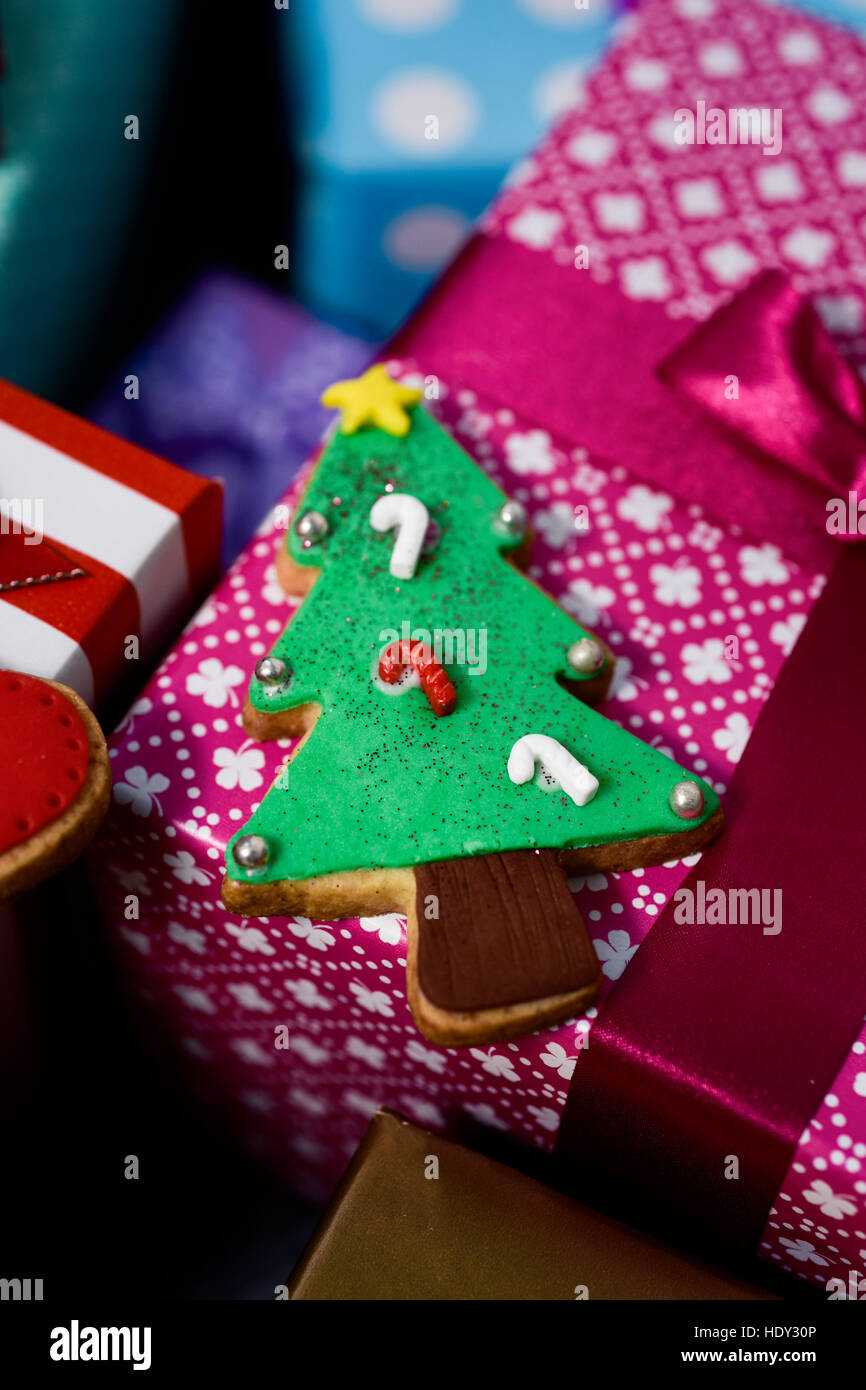 closeup of a christmas biscuit in the shape of a christmas tree on a pile of gifts wrapped in nice papers and tied with ribbons of different colors Stock Photo