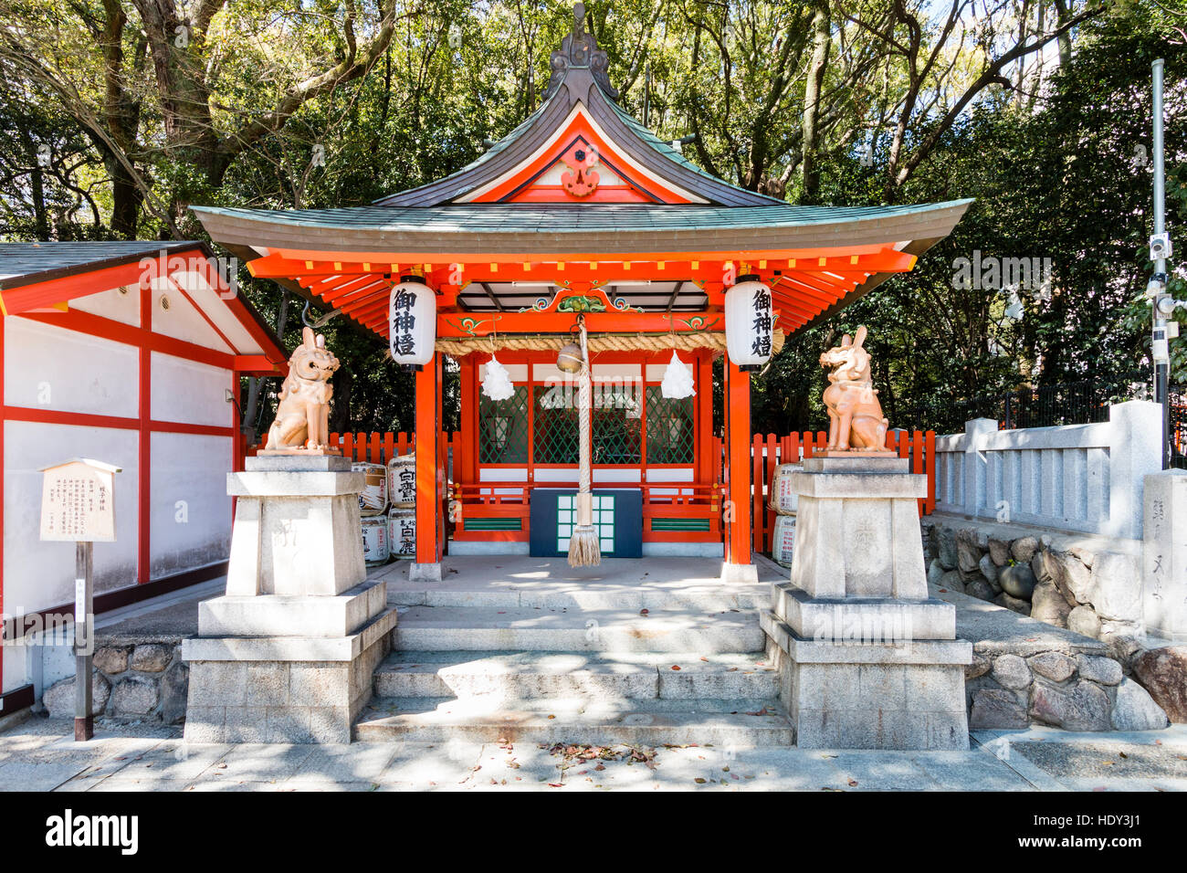 Famous Ikuta Shinto Shrine in Kobe, Japan. Small vermillion Sessha, setsumatsusha, auxiliary sub-shrine with lion-dog, komainu, guardians. Stock Photo