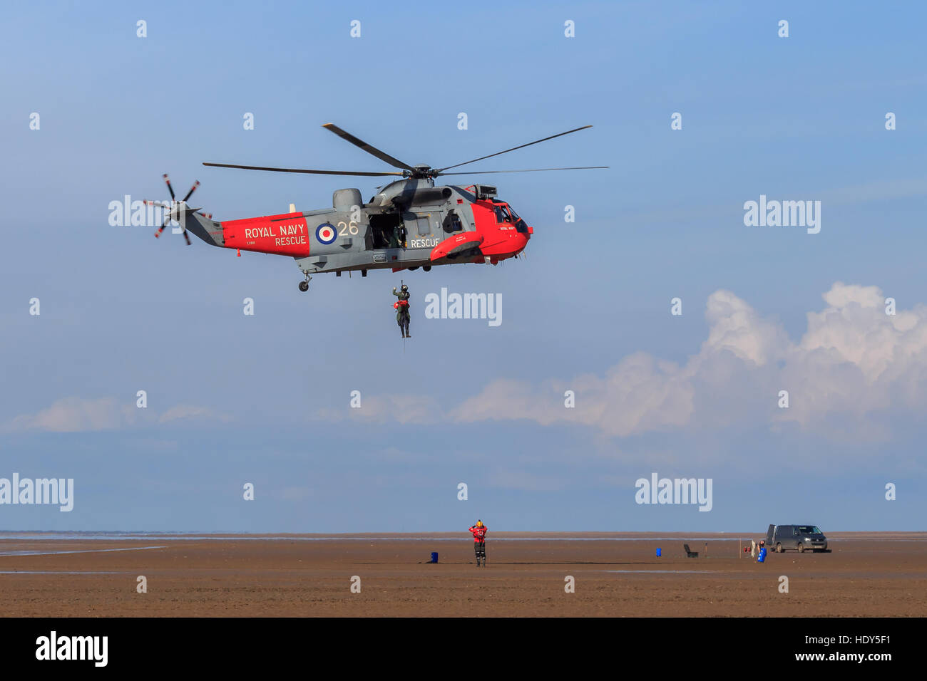 Royal Navy Seaking Search and Rescue helicopter performing mock rescue with crew member hanging from the winch Stock Photo