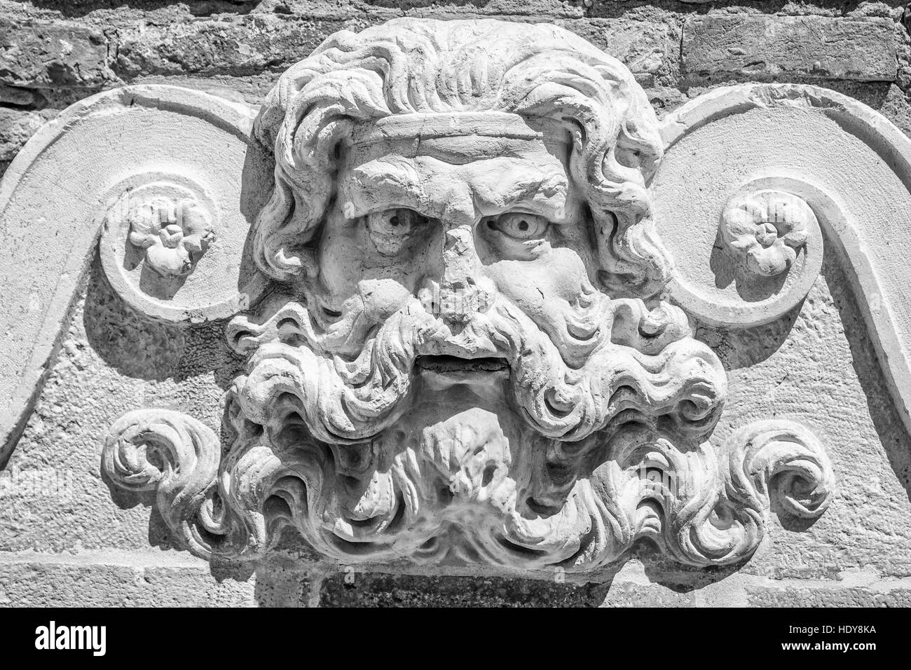 Detail of an ancient stone fountain depicting the god Neptune from whose mouth the water came out. Stock Photo