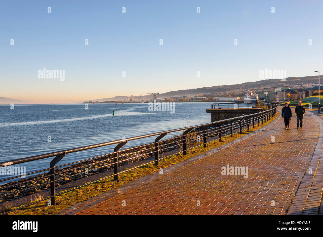 Two people walking alomg the new esplanade at Greenock on a cold winter morning With fog on the river. Stock Photo