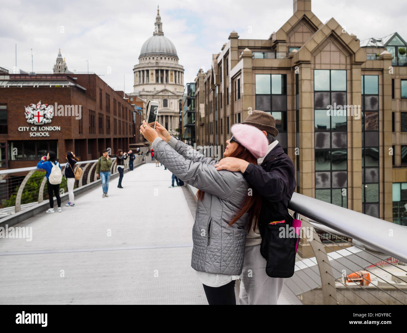 Couple using a tablet to take a selfie on the Millennium Bridge, London, England. Stock Photo