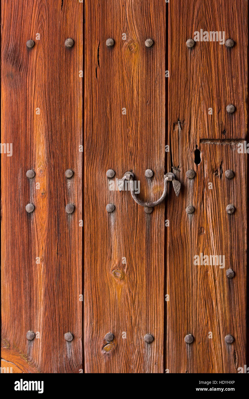 Very old wooden entrance door, thick, strong and weathered, a symbol for protection, dark brown background, copy or text space Stock Photo