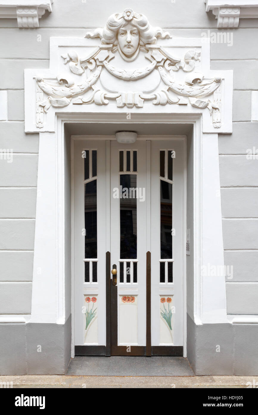Entrance door of an historic building with stucco in art nouveau style, sculpture of a womans head, gray and white, Hamburg Stock Photo