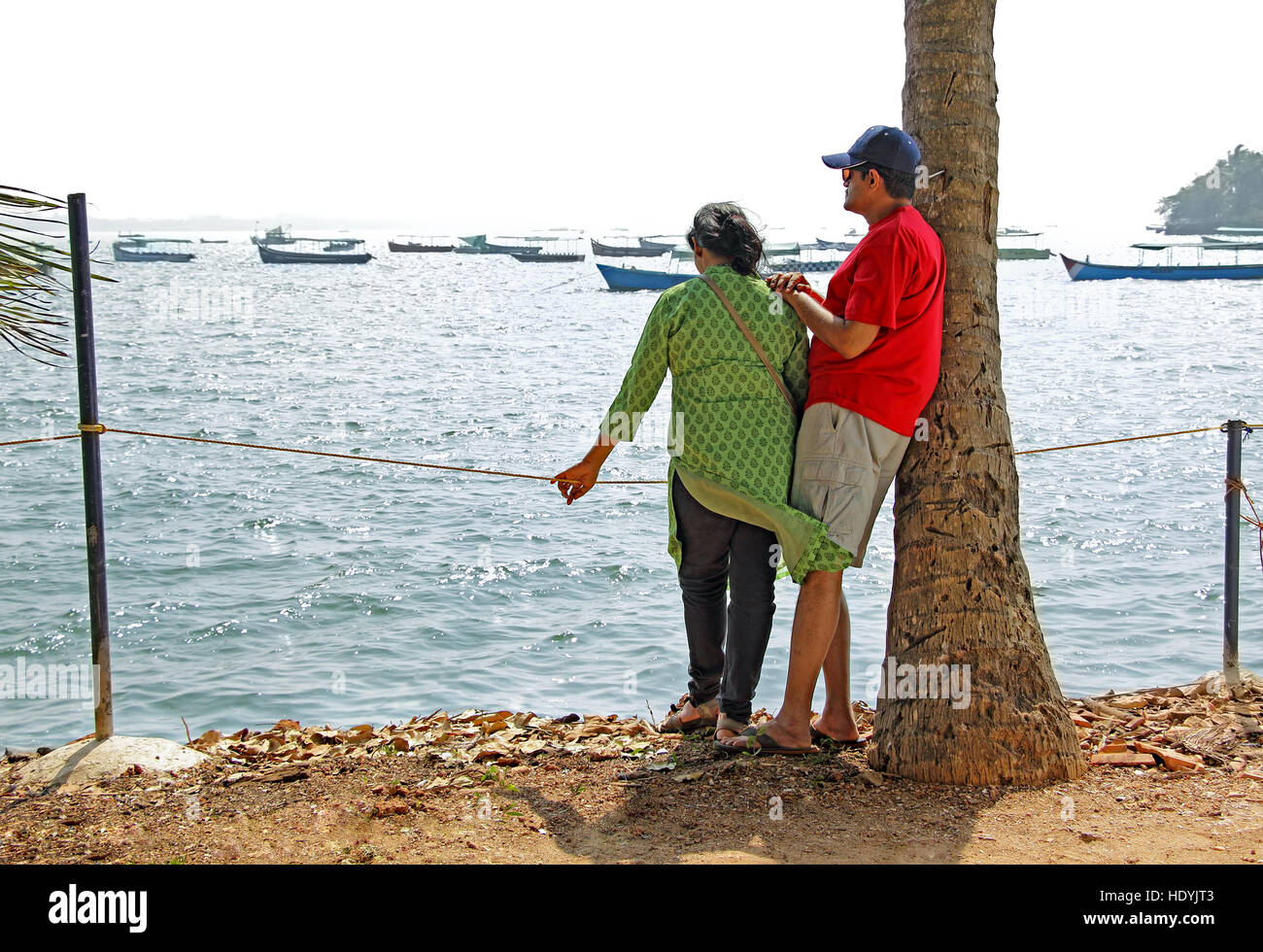 Asian adult couple watching boats anchored in a bay in Goa, India Stock Photo