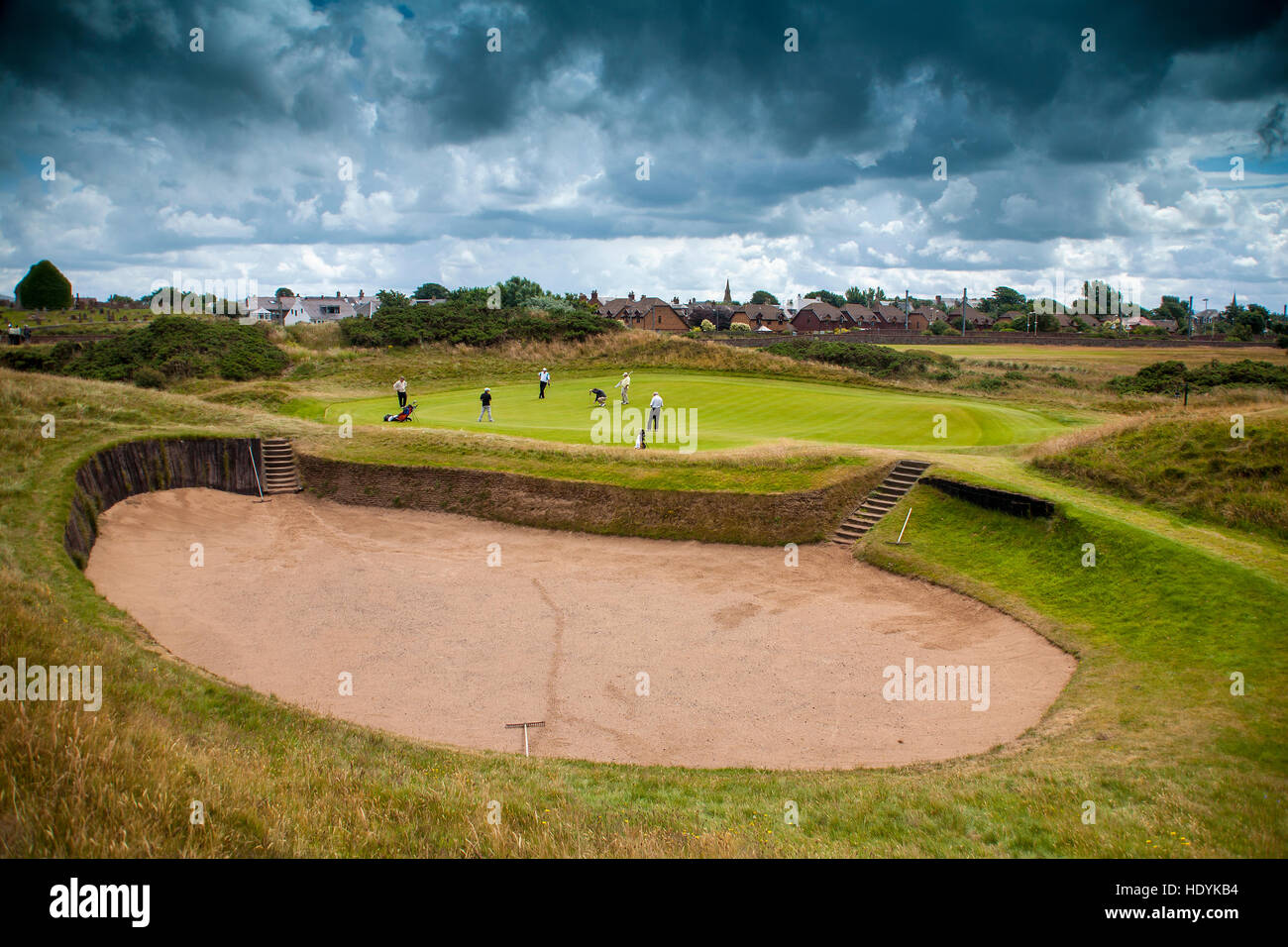 Prestwick Golf Club Green and huge bunker  under dark clouds threatening skies golf in Scotland Stock Photo