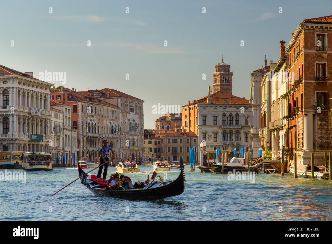 Venice gondola on Grand Canal in the evening sunlight on the water, gondolier and passengers. Stock Photo