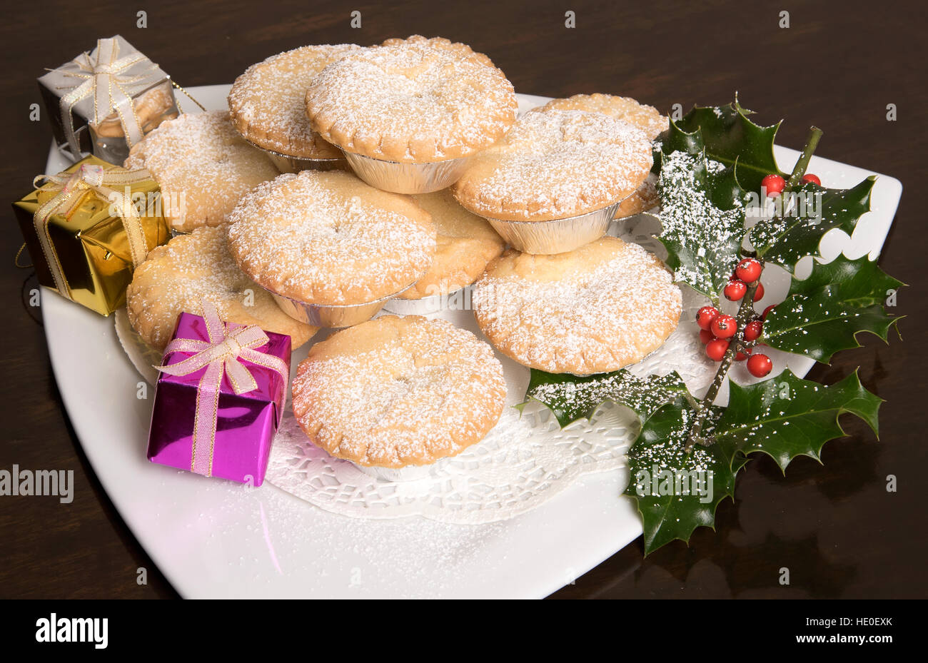Traditional Mince pies with a dusting of icing sugar on a white plate ...