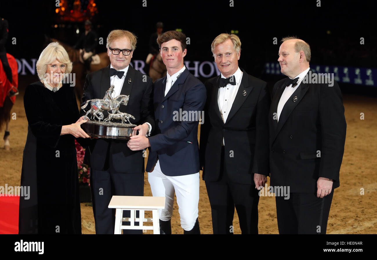 The Duchess of Cornwall (left) presents the Raymond Brooks-Ward trophy to Tim Wilks (centre) joined by Raymond Brooks-Ward's children from Simon Brooks-Ward (second left), James Brooks-Ward (second right) and Nick Brooks-Ward (right) during day three of the London International Horse Show at London Olympia. Stock Photo