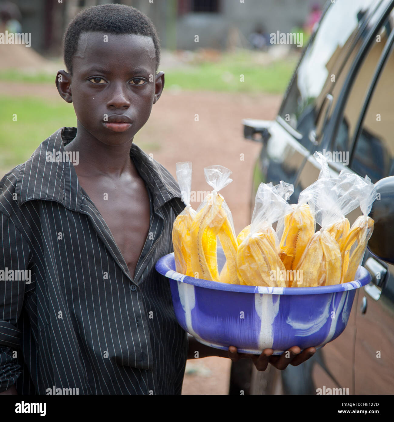 Boy offering banana chips. Wafer-thin banana chips made fresh are a treat that would be worth a trip to Sierra Leone for alone Stock Photo