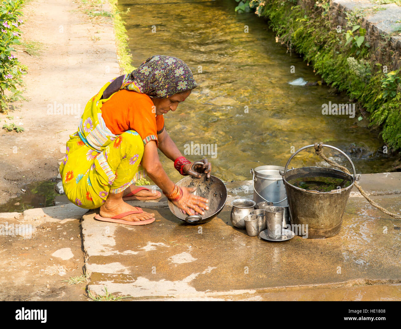 Indian woman washing pans at Boar Canal, Chotti Haldwani, Kaladunghi, Uttarakhand, India Stock Photo