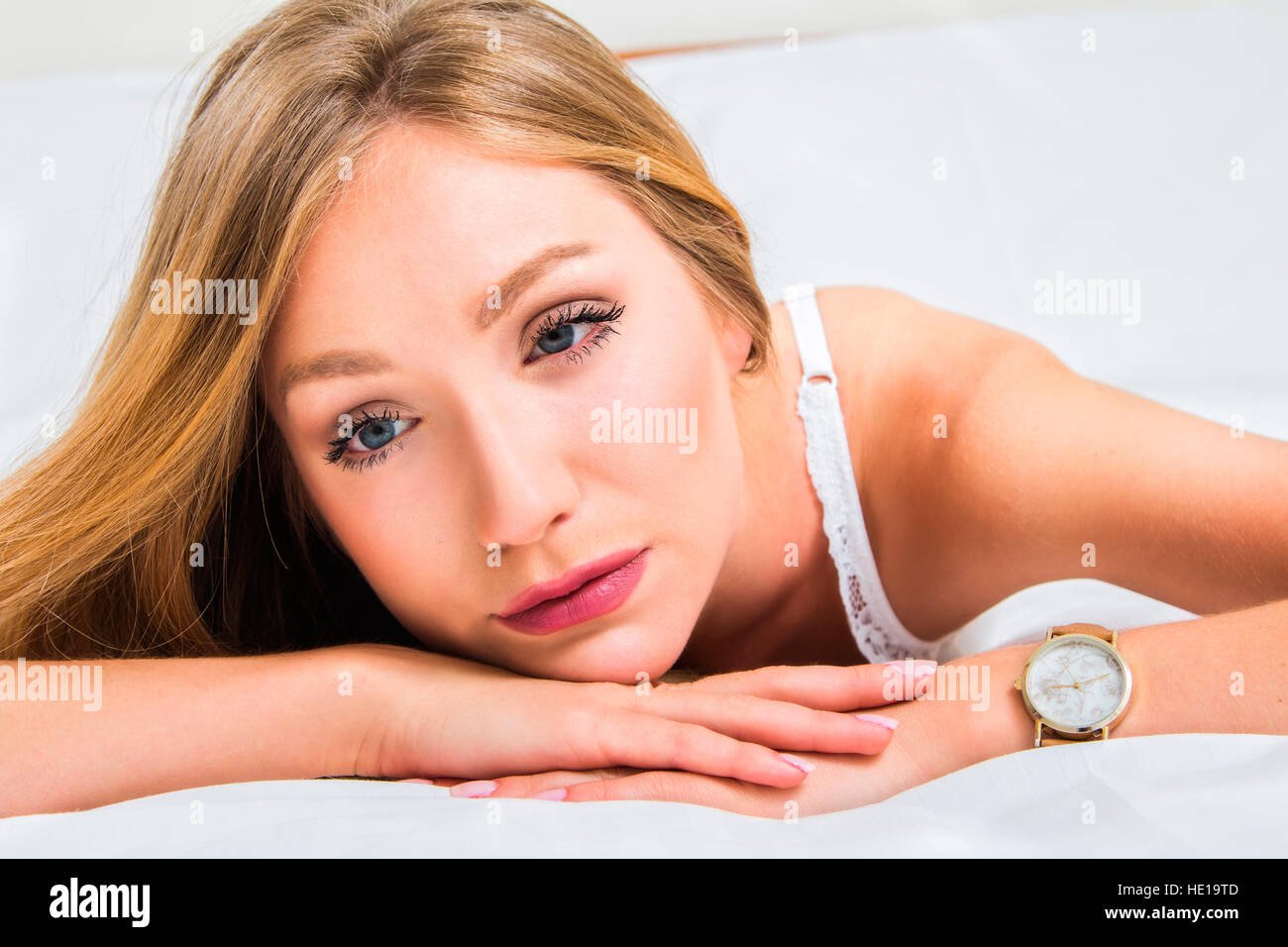 Sexy girl in white lace underwear lying on the bed, looking sad and alone  Stock Photo