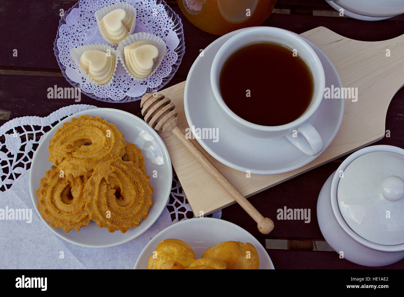 A cup of tea with honey, milk, butter and vanilla biscuits and white
