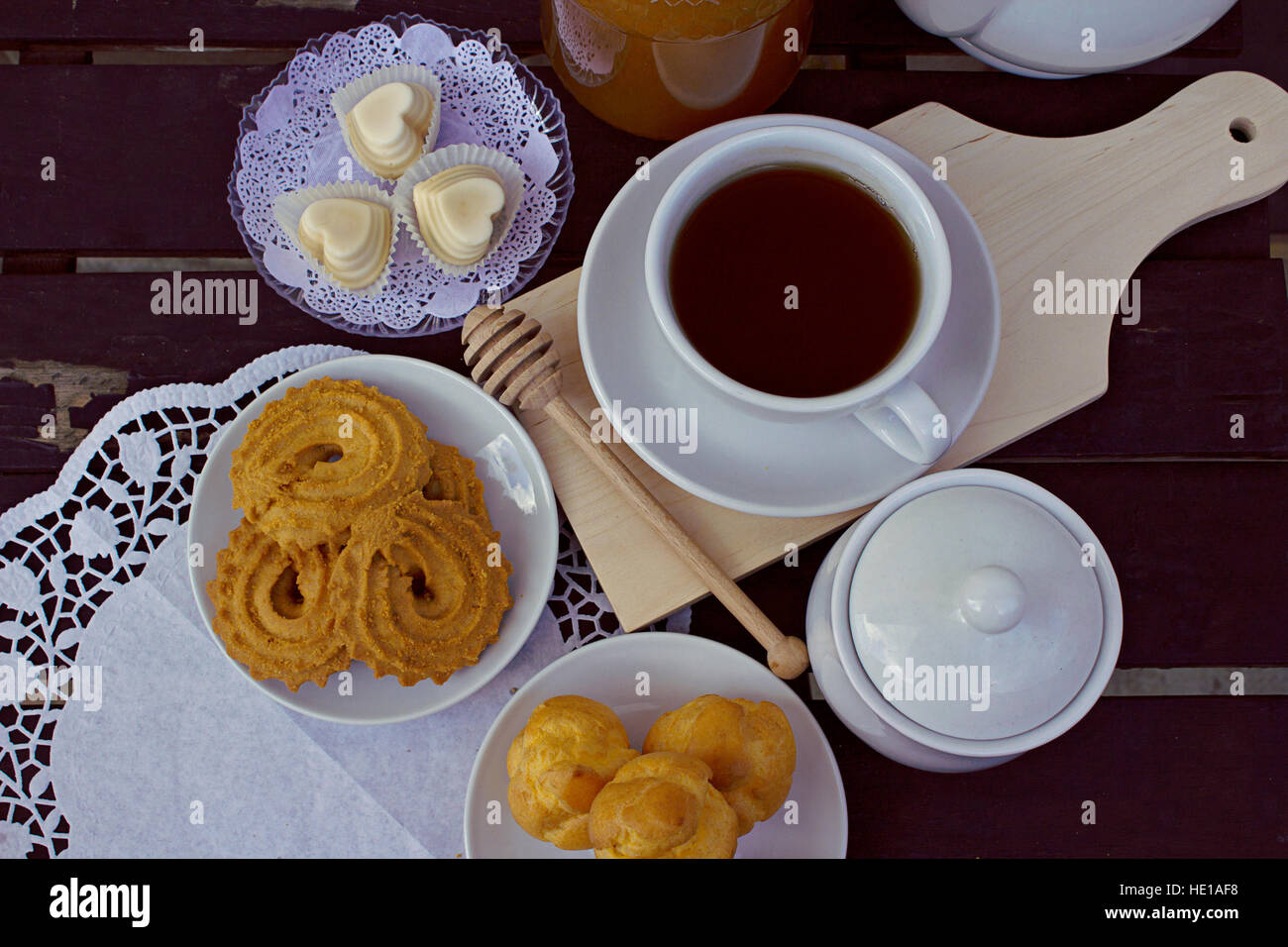 A cup of tea with honey, milk, butter and vanilla biscuits and white