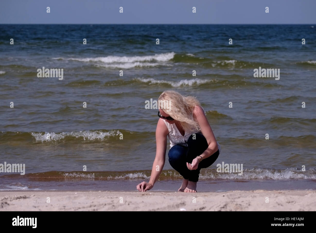 Young Lithuanian woman collecting seashells at the northern seacoast of ...