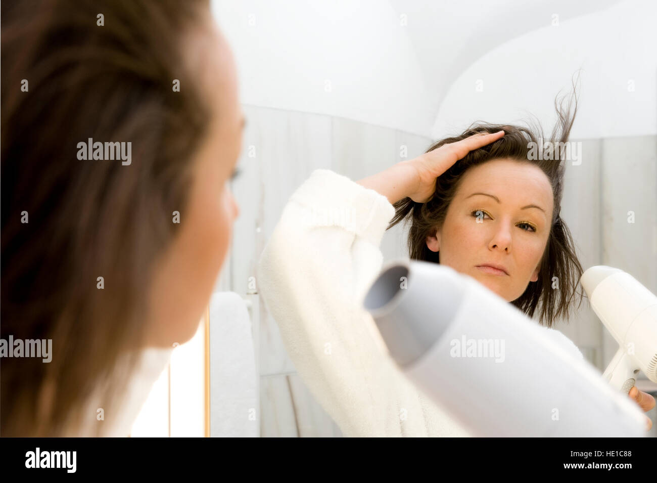 Young woman blow drying her hair in the bathroom Stock Photo - Alamy