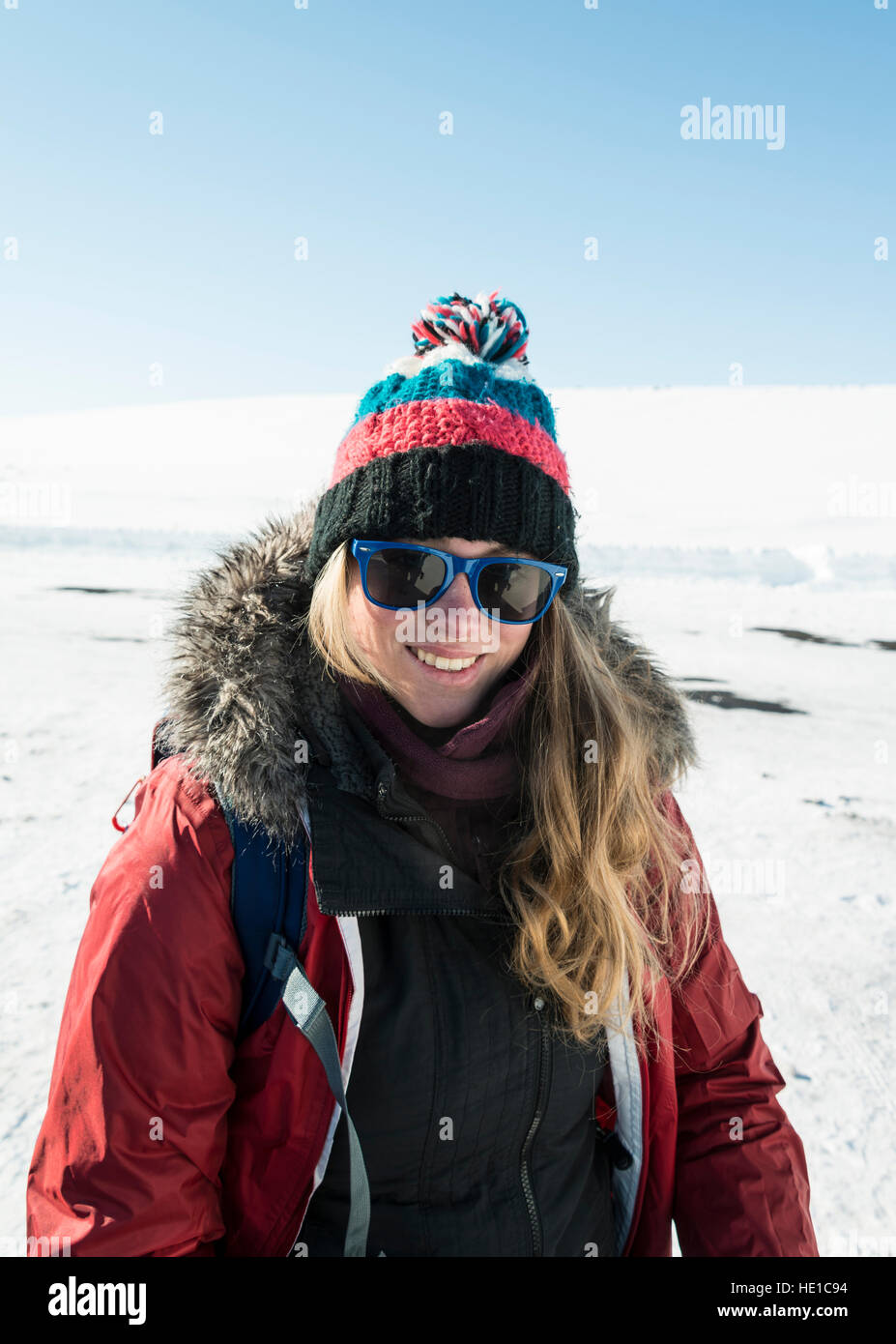 Young woman wearing winter jacket and woolly hat, smiling, snowy landscape, Iceland Stock Photo