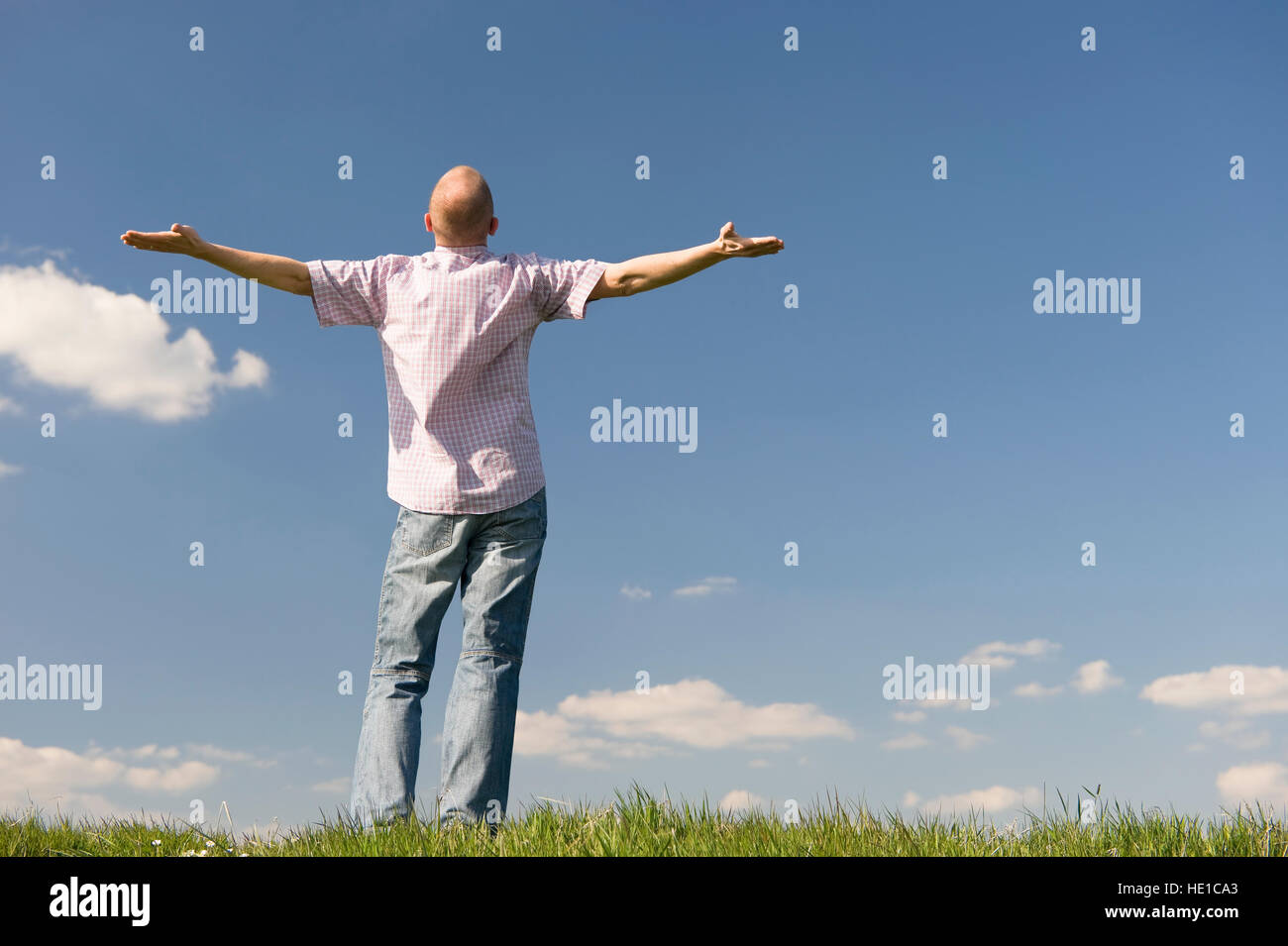Young man standing on a meadow with outstreched arms Stock Photo