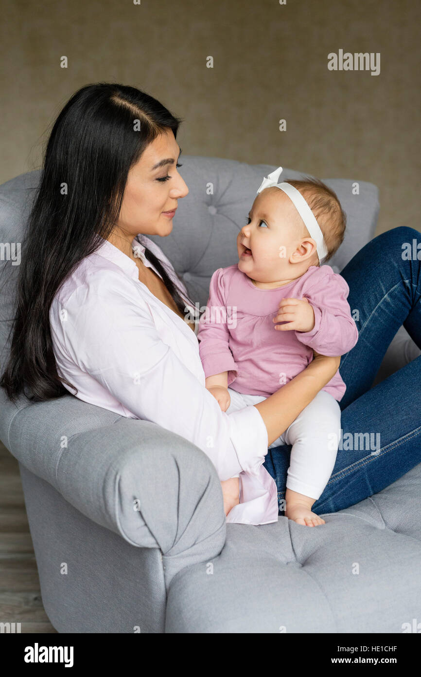 Mother is sitting with baby on an armchair Stock Photo