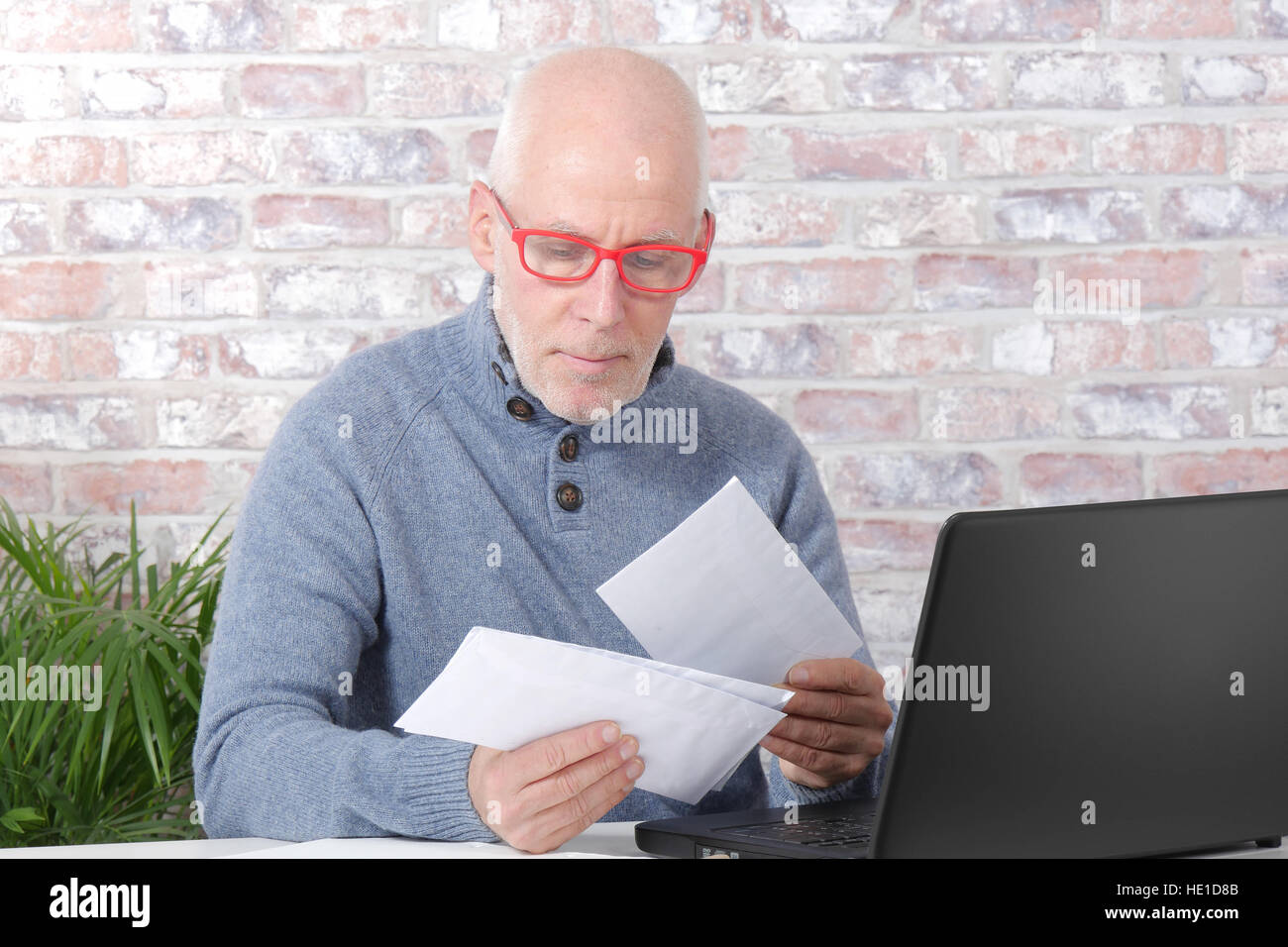 handsome mature man opening letter envelope in his office Stock Photo