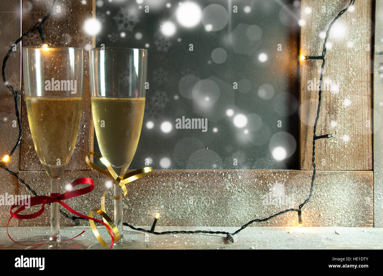 Two champagne glasses next to an empty chalkboard with lights Stock Photo