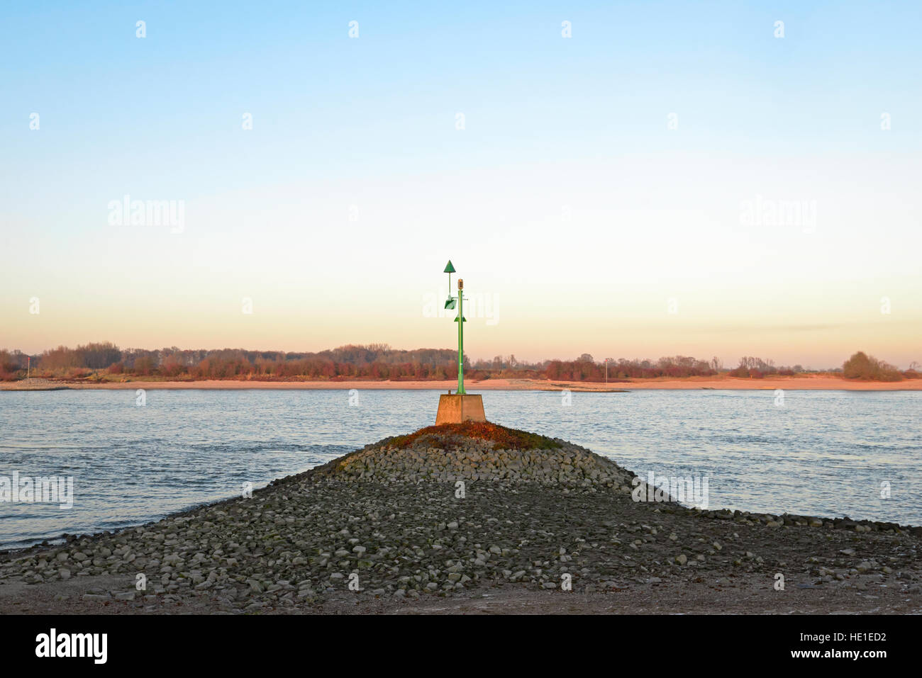 Green beacon in the river Waal in the evening sun Stock Photo
