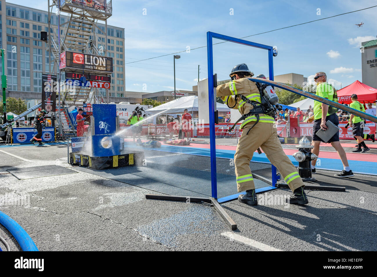 A firefighter completing a timed event with a fire hose. Stock Photo