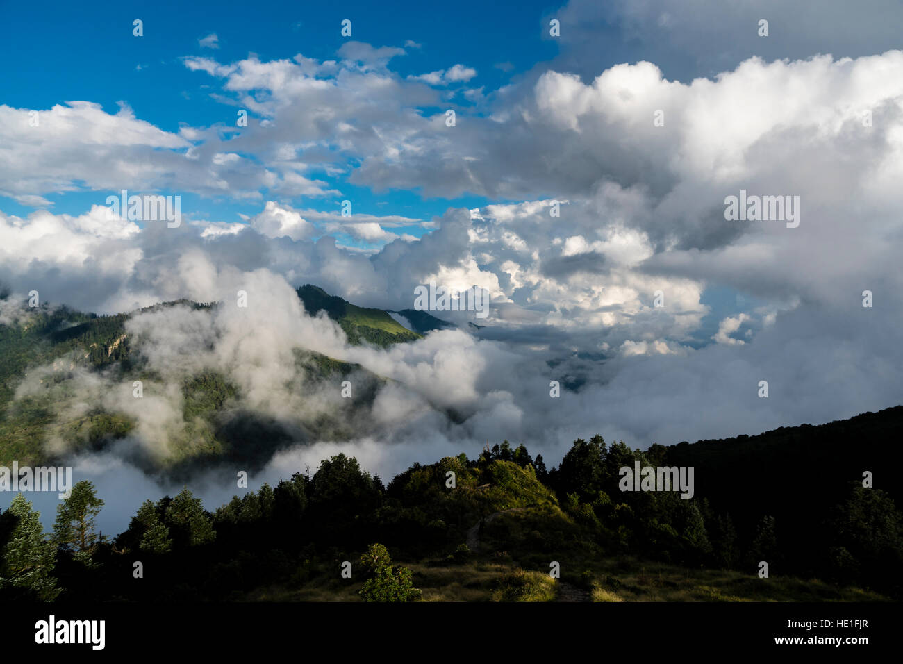 Hilly Landscape with monsoon clouds and blue sky, seen from Poon Hill Stock Photo