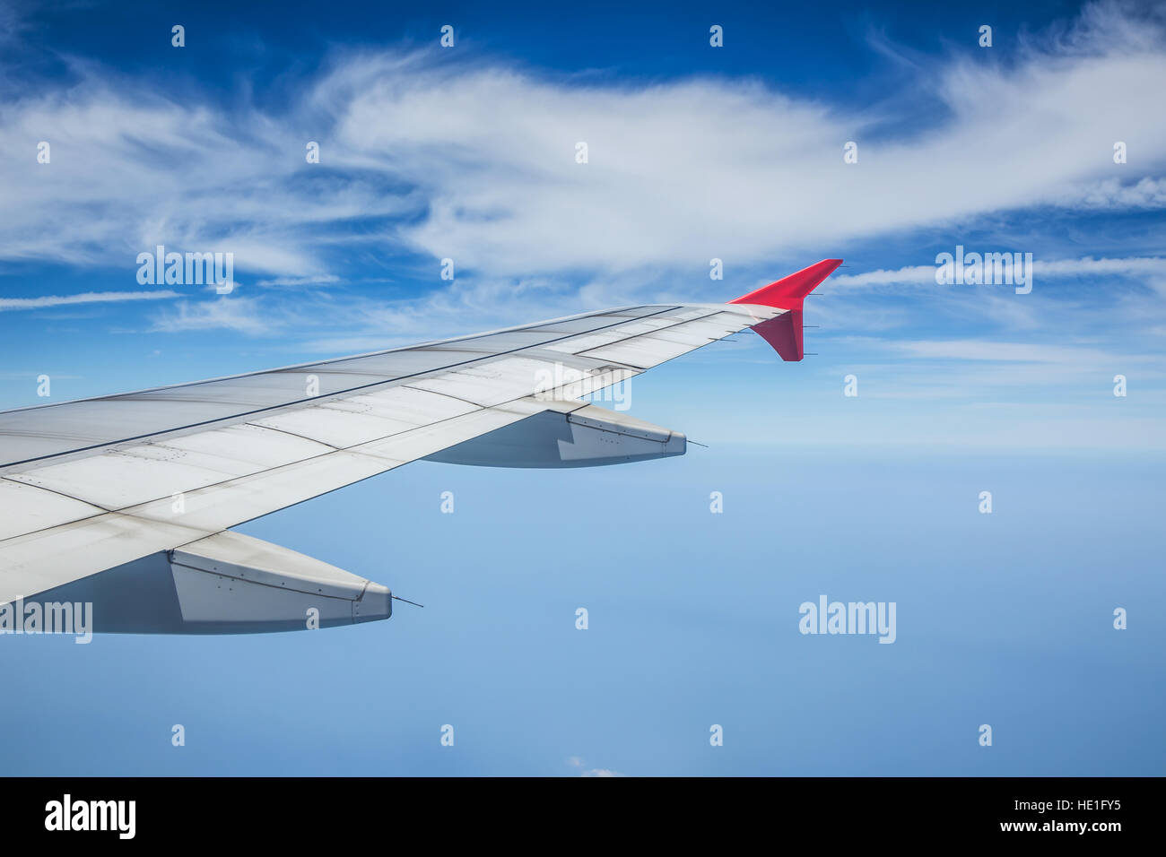 Wing of airplane flying above the clouds in the blue sky Stock Photo ...