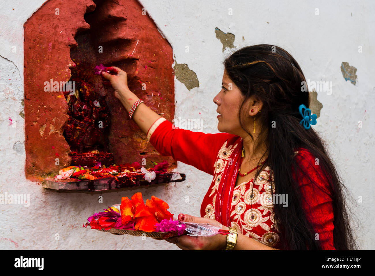 A woman is offering prasad to the statues of gods outside the temple Khadga Devi Mandir at the hinduist festival Darsain Stock Photo