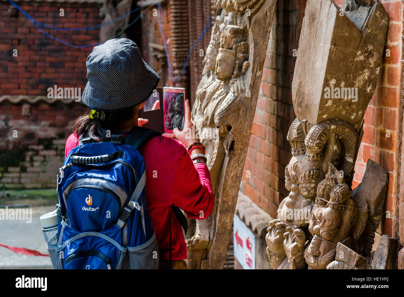 A chinese woman is taking a photograph of the artfully carved wooden figures at the Hanuman Dhoka Palace Stock Photo