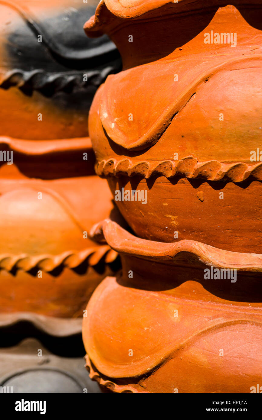 Big terracotta clay pots with ornaments are piled up for sale Stock Photo