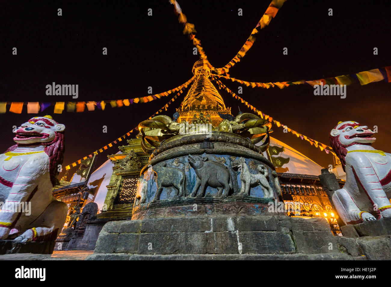 The white stupa of Swayambhunath temple, Monkey Temple, is decorated with tibetan prayer flags and illuminated at night Stock Photo